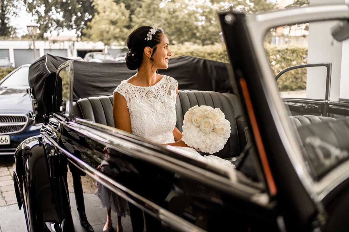 Braut mit Brautstrauß in einer schwarzen Limousine