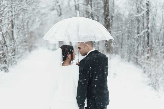 Peggy Will Agentur Traumhochzeit München Winterhochzeit Brautpaar im Schnee unter Regenschirm